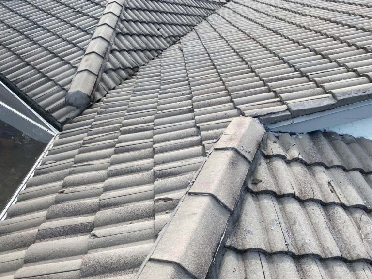 Roofer inspecting a gray tile roof in Sarasota
